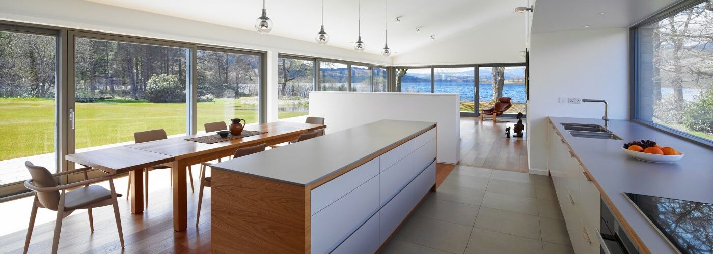 an open plan kitchen with a wall of glass made from lift and slide glass doors